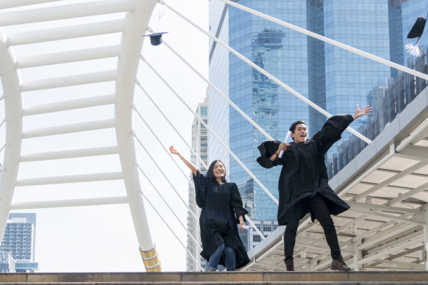 快乐的毕业生们穿着毕业礼服在庆祝仪式上跳来跳去。图片下载