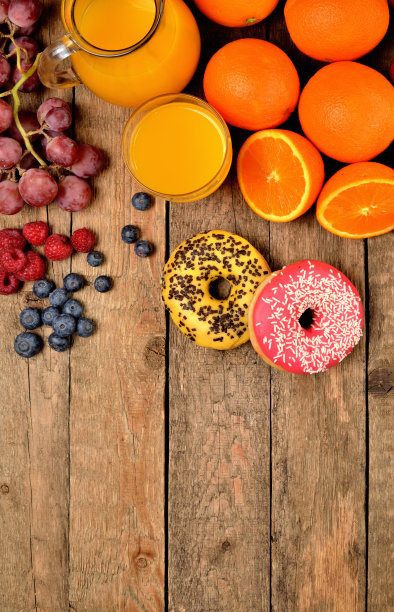 甜甜圈，橙汁，蓝莓，树莓，苹果，橘子-甜早餐在木制桌子上-从上面看，垂直照片图片下载