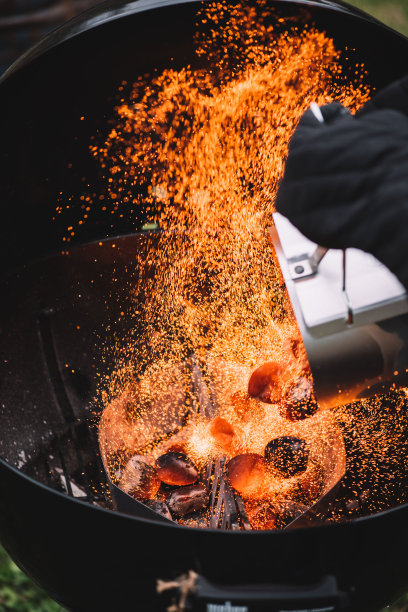 火焰火花捕捉的时刻，把热的木炭从火的起动机到木炭烧烤架，近距离观看图片下载