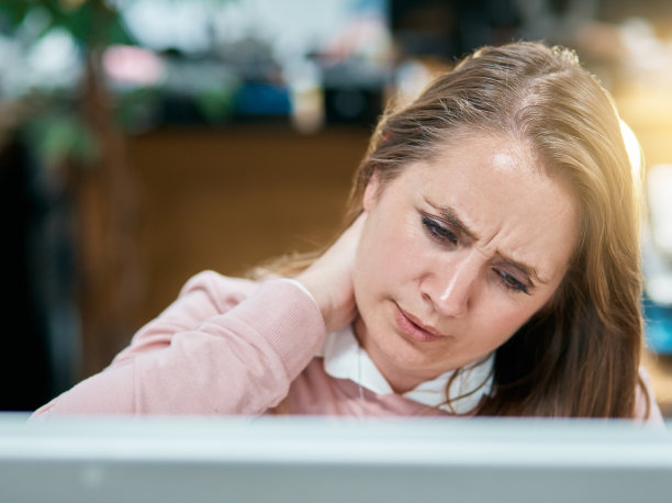 一位女职员皱着眉头，揉着脖子，向下看图片下载