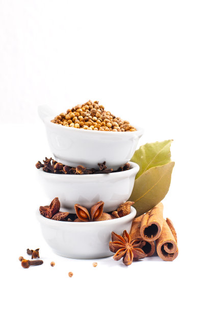 混合有机香料肉桂棒，月桂叶，八角和香菜籽在白色背景的白色陶瓷杯图片下载