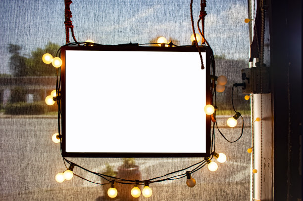 商店橱窗里挂着空白的标牌，周围是派对灯光，后面是半透明的深色遮阳板，外面是模糊的城市街道图片下载