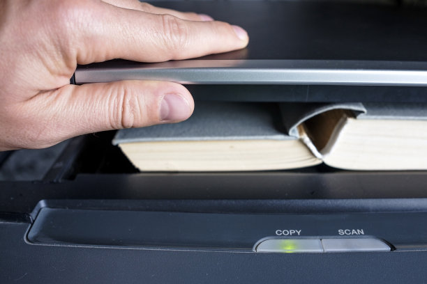 一名男子将一本书放入复印装置中图片下载