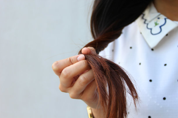 女人手握着她的长发，看着头发残缺分叉的护理问题图片下载