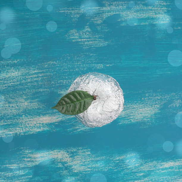 一个苹果在破旧的蓝色背景上，用箔纸包着绿叶。图片下载