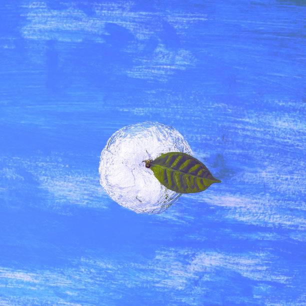 一个苹果在破旧的蓝色背景上，用箔纸包着绿叶。图片下载