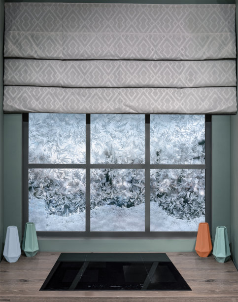 一个舒适的现代厨房，木制的桌面和电磁炉。木窗与罗马窗帘和透过冰冻玻璃与冰图案图片下载