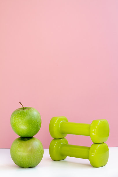 为健康的生活做准备新鲜的绿色苹果和哑铃健身在粉红色的背景图片下载
