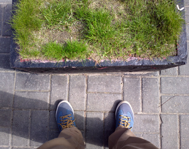 双脚踩在沥青上。草。鹅卵石。图片下载