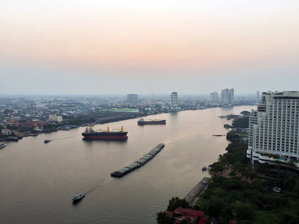 傍晚，以城市为背景的河上运输船景观图片下载