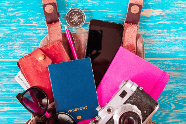 背包里的东西。旅行的概念。护照钱太阳镜上的蓝色木制背景。本空间图片下载