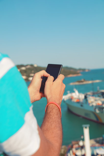 男人一边玩手机一边欣赏风景。图片下载