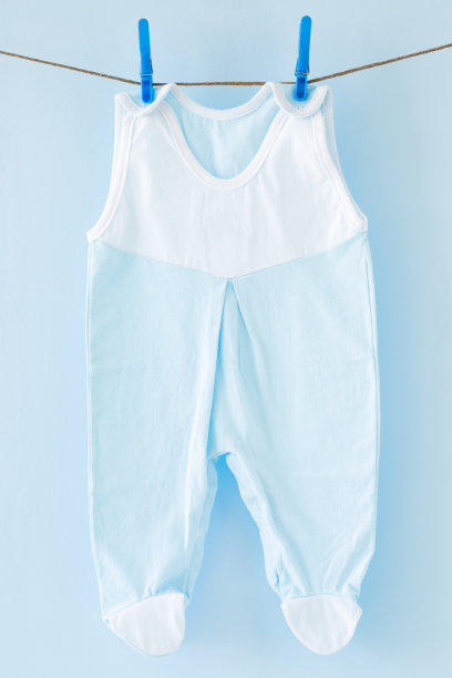 新鲜，干净的婴儿紧身衣在洗衣绳上干燥，在淡蓝色的背景。干洗。定期清洗。衣服护理。母亲和父亲的责任。日常生活。图片下载