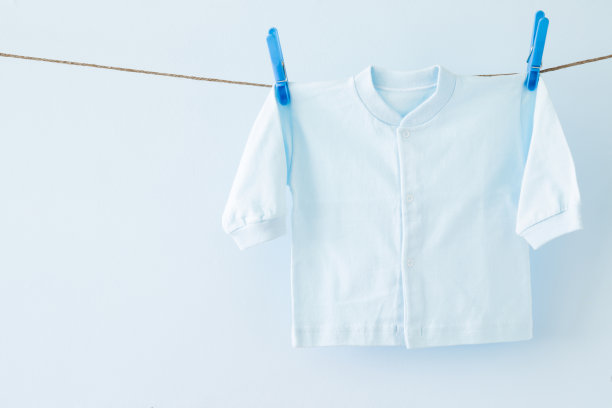 新鲜，干净的婴儿衬衫在洗衣绳上，柔和的蓝色背景。干洗。定期清洗。衣服护理。母亲和父亲的责任。日常生活。文本的空位置。图片下载