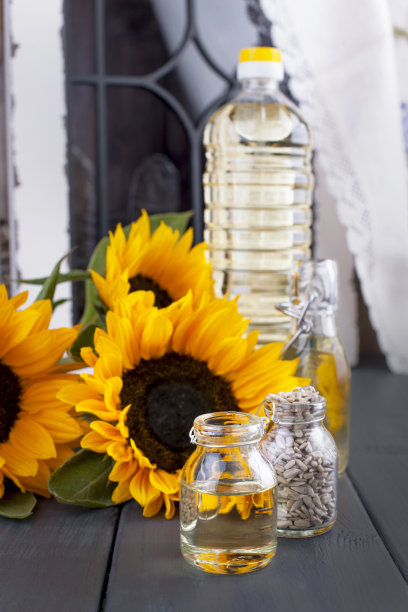 窗户附近的向日葵油和大型黄色花朵，瓶子里的油，没有葵花籽皮，复古照片，有机食品图片下载