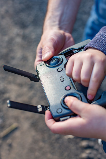 父子手握遥控操纵杆，驾驶四轴飞行器图片下载