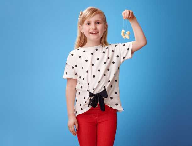 微笑的现代女孩在红色的裤子在蓝色显示大蒜珠子图片下载