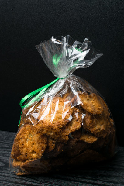 自制的燕麦饼干装在袋子里放在木桌上，用绿丝带装饰。健康食品和零食的概念。本空间图片下载