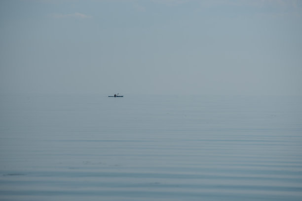 在日出时在平静的波罗的海上划桨的皮划艇运动员图片下载