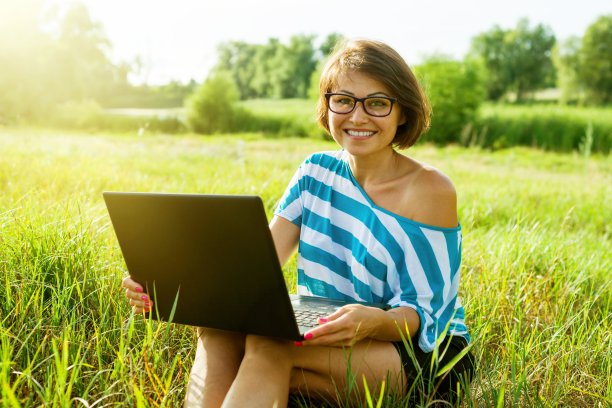 成年美女在户外使用笔记本电脑。图片下载