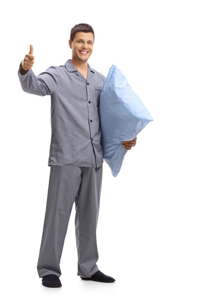 穿着睡衣的年轻人拿着一个枕头，竖起大拇指图片下载