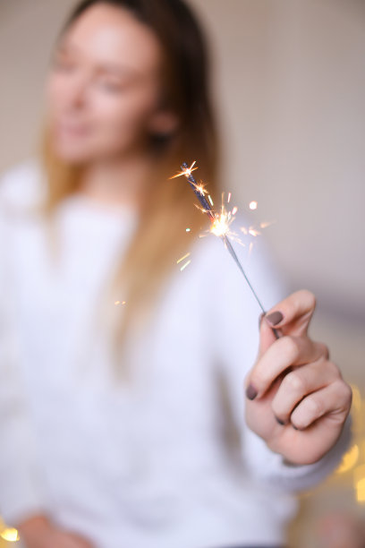 模糊照片的金发美女坐近近孟加拉光闪烁的黄色花环图片下载