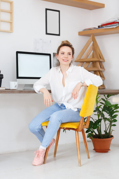 音乐会的成功美丽的年轻女子。设计师或插画家坐在办公桌前，用白色背景的大电脑。文本的地方图片下载