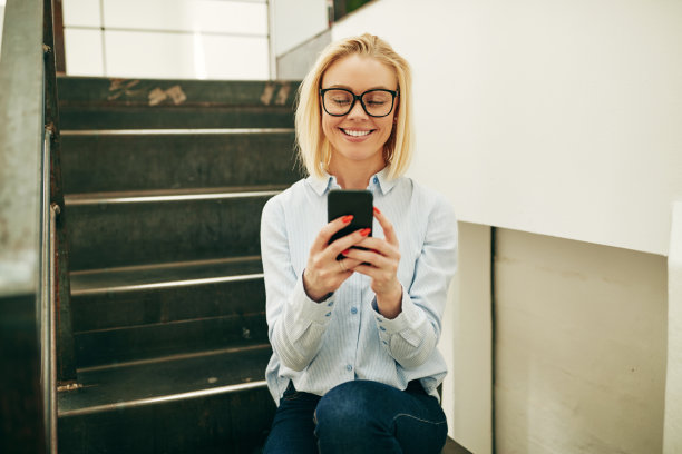 女商人微笑着坐在办公室楼梯上读文章图片下载