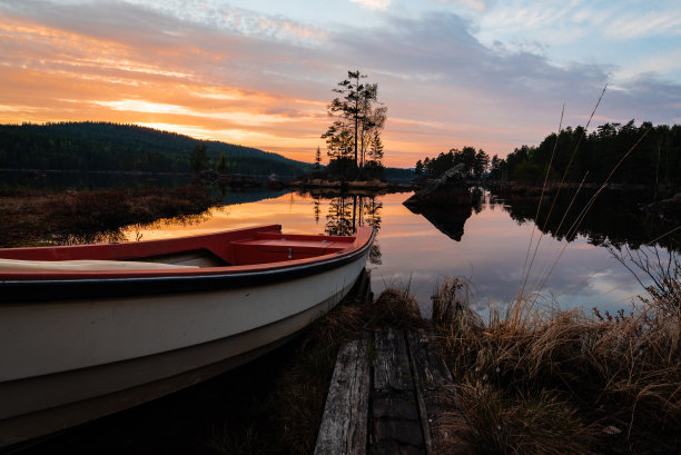 小船靠近平静的湖在日落。图片下载