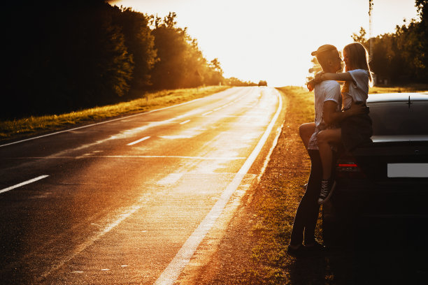 一对情侣在日落时分的汽车拥抱图片下载