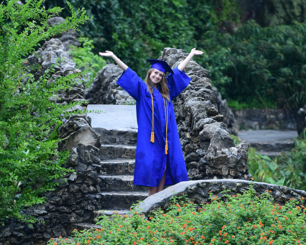 年轻女孩摆姿势的高中毕业照片与帽子和长袍图片下载