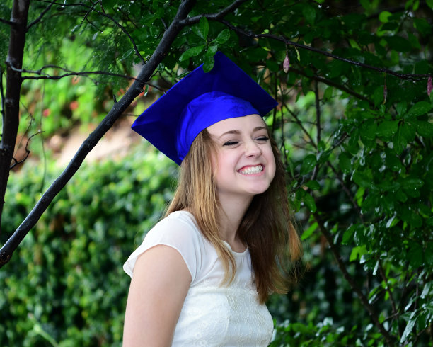 年轻女孩摆姿势的高中毕业照片与帽子和长袍图片下载