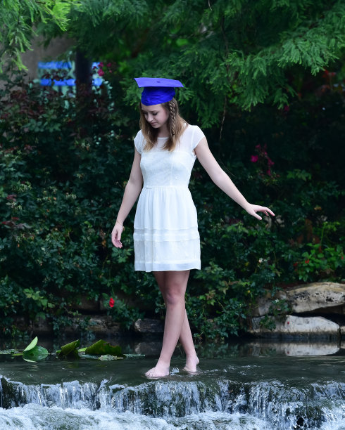 年轻女孩摆姿势的高中毕业照片与帽子和长袍图片下载