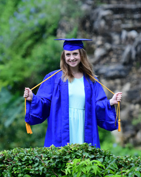 年轻女孩摆姿势的高中毕业照片与帽子和长袍图片下载