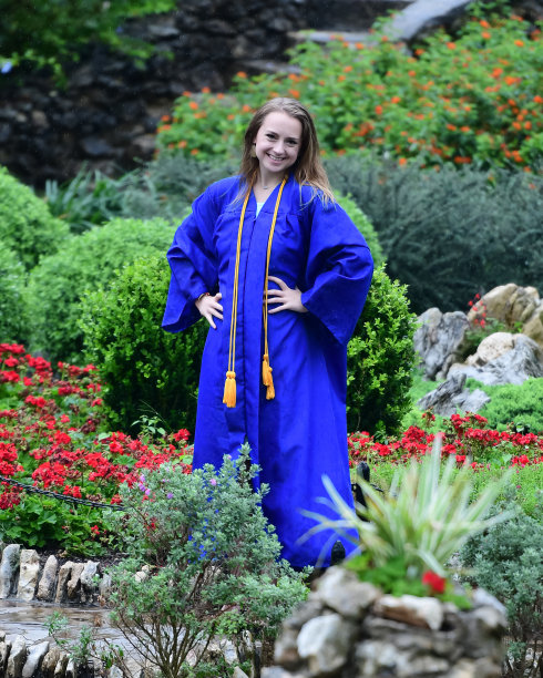 年轻女孩摆姿势的高中毕业照片与帽子和长袍图片下载