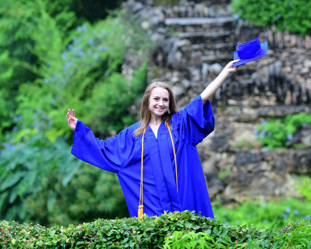 年轻女孩摆姿势的高中毕业照片与帽子和长袍图片下载