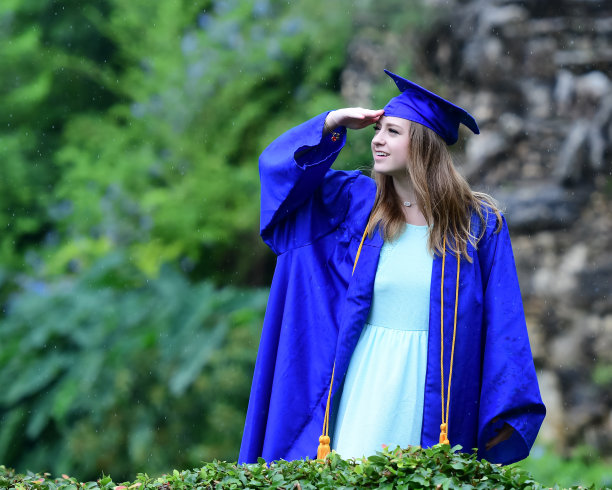 年轻女孩摆姿势的高中毕业照片与帽子和长袍图片下载