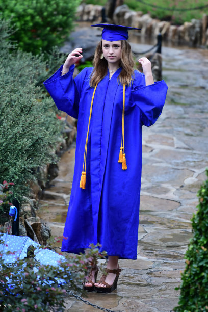 年轻女孩摆姿势的高中毕业照片与帽子和长袍图片下载