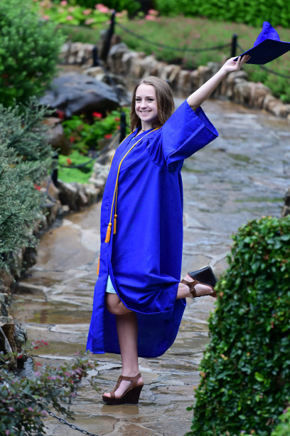 年轻女孩摆姿势的高中毕业照片与帽子和长袍图片下载