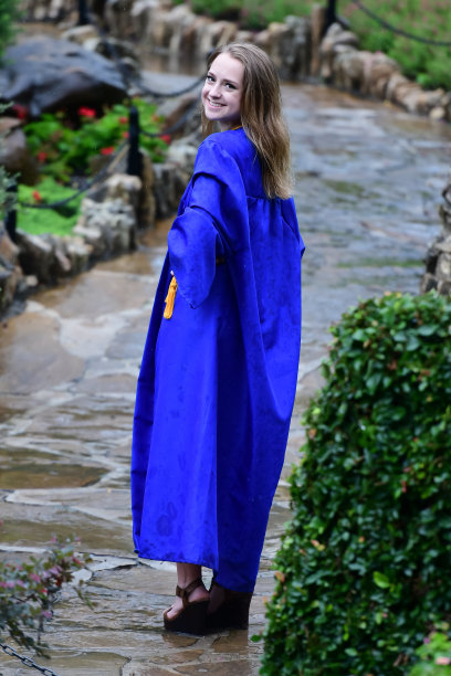 年轻女孩摆姿势的高中毕业照片与帽子和长袍图片下载