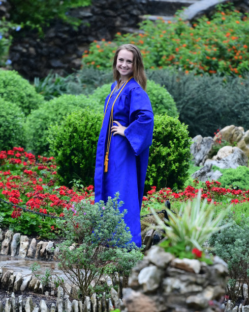 年轻女孩摆姿势的高中毕业照片与帽子和长袍图片下载