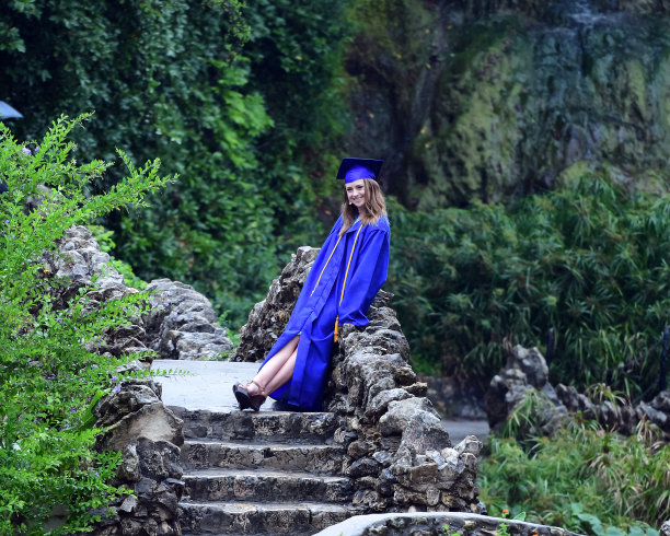 年轻女孩摆姿势的高中毕业照片与帽子和长袍图片下载