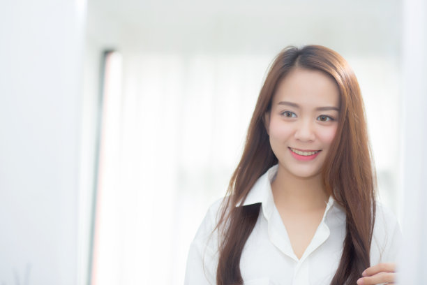 肖像美丽的亚洲年轻女子审视与脸和微笑看着镜子在卧室，女孩美化妆和打扮反射，生活方式和健康的概念。图片下载