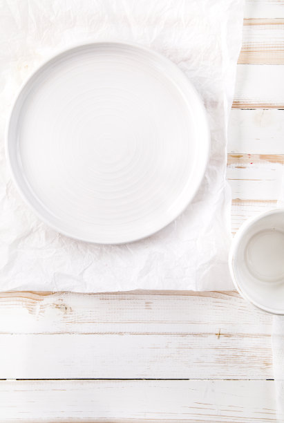 一套不同的陶瓷盘子和碗风格的白色心疼木制背景。垂直的构图。平铺与拷贝空间图片下载
