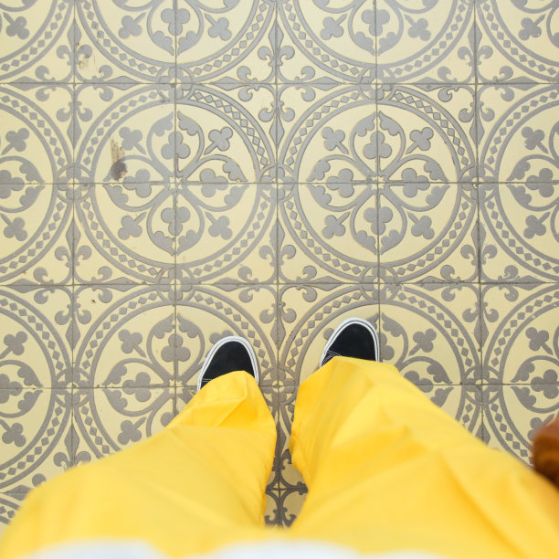 脚的时尚自拍照片。运动鞋和黄色trausers在艺术图案摩洛哥风格瓷砖地板上，俯视图图片下载
