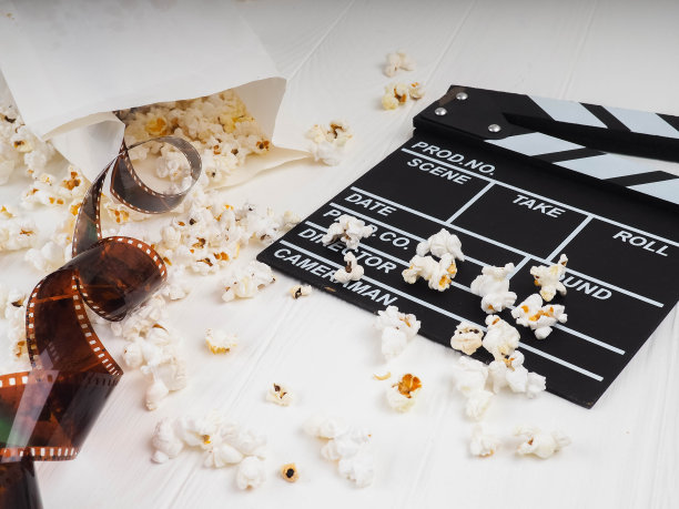 影片在螺旋形、靠近爆米花、克拉珀板的复制空间为文本，时尚亮点在照片、概念、电影行业、电影、抽象构成的电影中，在白色的背景上图片下载