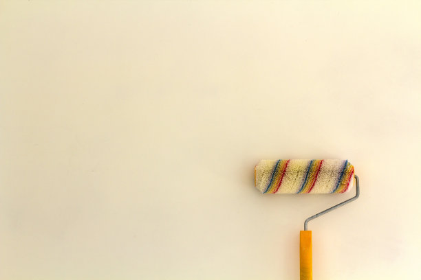 油漆辊刷在装修房间的墙壁附近，室内隔离在白色背景。翻新和DIY的概念。图片下载