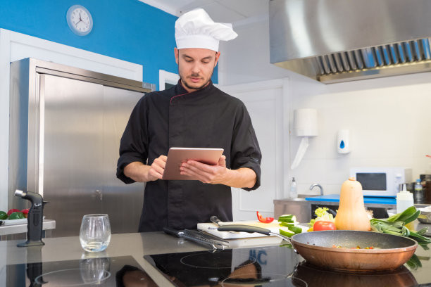 年轻的厨师长通过互联网在平板电脑上查阅他的食谱图片下载
