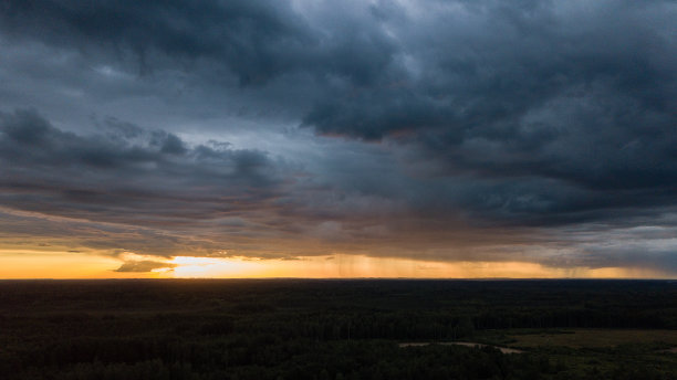 无人机图像。鸟瞰图的农村地区与房屋和道路下大雨和黑暗的戏剧性的乌云在夏天的一天。晚上的照片图片下载