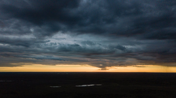 无人机图像。鸟瞰图的农村地区与房屋和道路下大雨和黑暗的戏剧性的乌云在夏天的一天。晚上的照片图片下载